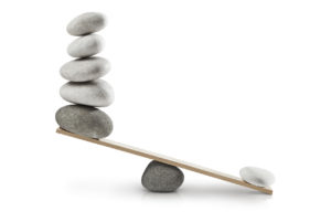 scale with large pile of rocks on one side, one small rock on the other so it is imbalanced