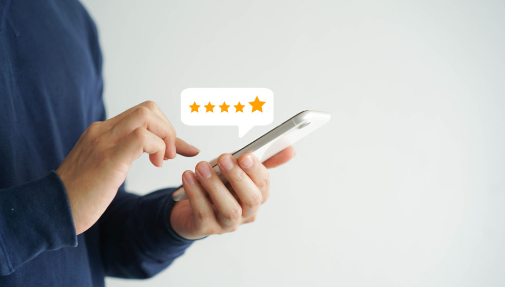 close up on customer man hand pressing on smartphone screen with  five star rating feedback 
