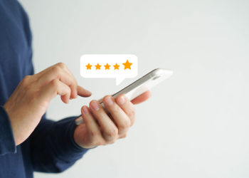 close up on customer man hand pressing on smartphone screen with five star rating feedback