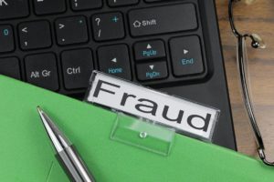 Folder labeled Fraud over a computer keyboard