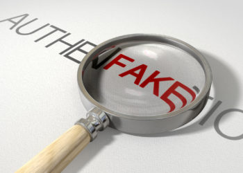 image of a magnifying glass with a wooden handle on a textured white surface showing the word authentic but magnifying the word fake resembling counterfeiting