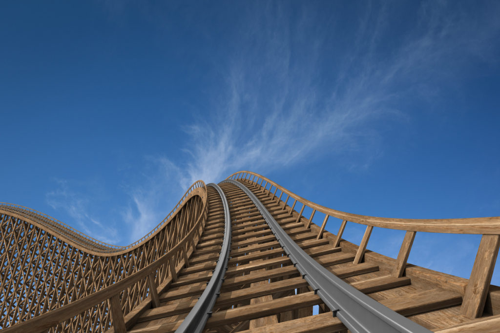 Wooden roller coaster track with blue sky in the background.