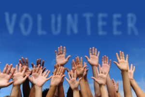 volunteer group raising hands against blue sky