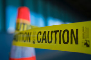 Yellow caution tape attached to traffic cone