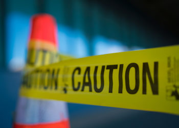Yellow caution tape attached to traffic cone