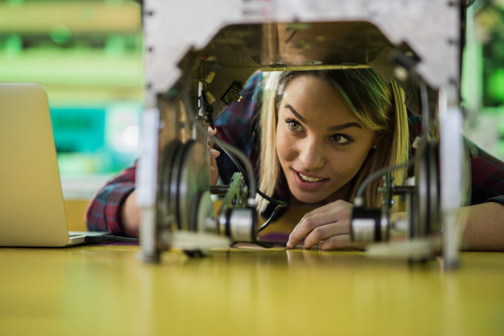 Young happy woman working on a robot in laboratory