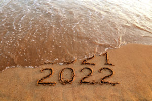 Numbers 2022 and 2021 drawn on sandy beach with waves