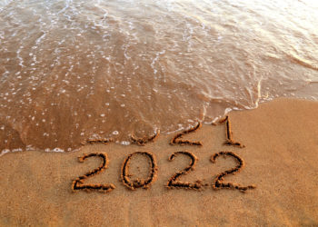 Numbers 2022 and 2021 drawn on sandy beach with waves