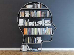 head-shaped bookshelf in front of black wall