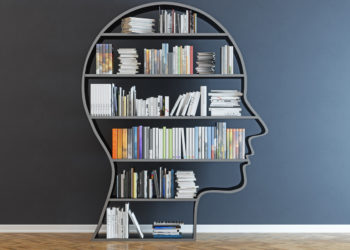 head-shaped bookshelf in front of black wall