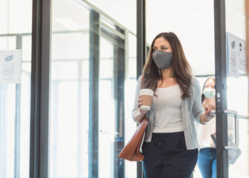businesswoman enters her office with face mask