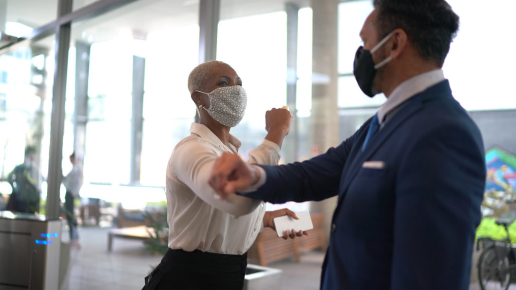 masked business people greeting by elbow bumping