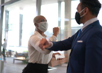 masked business people greeting by elbow bumping