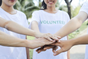 volunteers stacking hands to express support and unity before starting work
