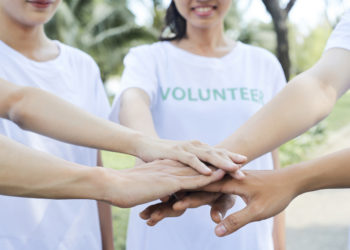 volunteers stacking hands to express support and unity before starting work