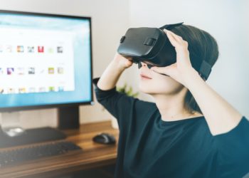 Person in front of computer screen wearing VR goggles
