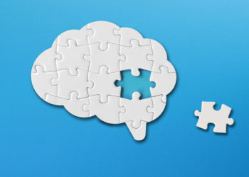 Brain shaped white jigsaw puzzle on blue background, with a missing piece of the brain puzzle