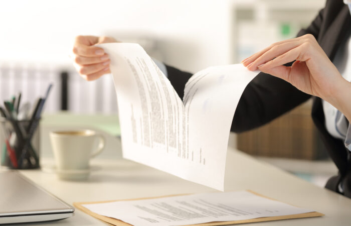 Close up of business woman hands tearing contract document sitting on a desk at the office
