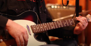 music video screen grab of hands strumming guitar