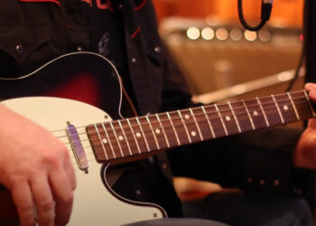 music video screen grab of hands strumming guitar