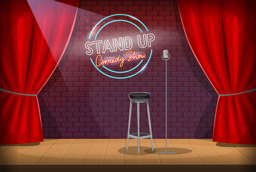 Scene of a comedy club with microphone, red curtains, chair and stand-up comedy show logo on a red brick wall