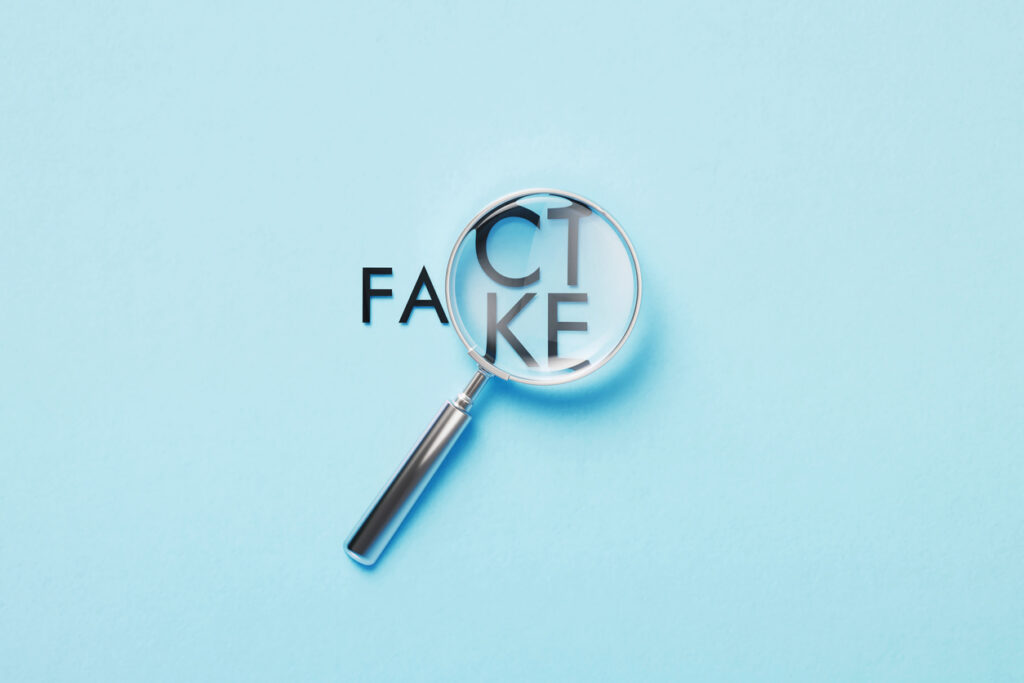 Magnifier over fact or fake words on blue background.