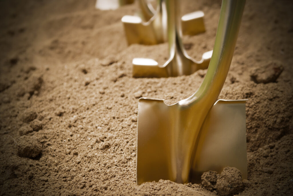 Gold shovels stuck in the dirt, in preparation of a groundbreaking ceremony