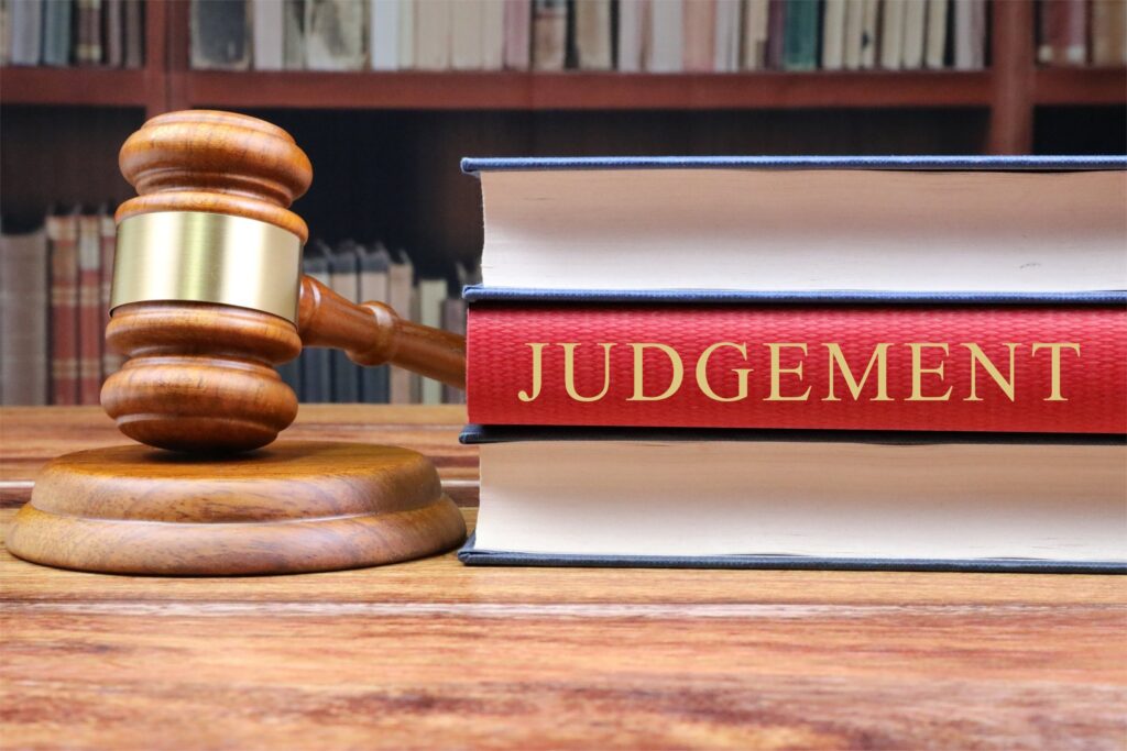 A gavel and a stack of books with one titled Judgement