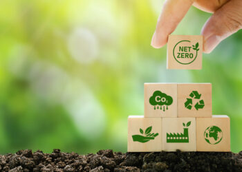 Hand stacking wooden blocks with net zero and other environmental logos on them