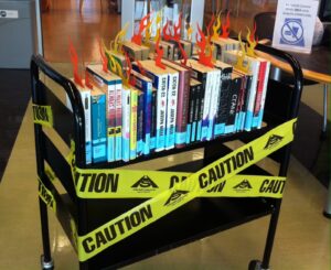 A cart of library books with "Caution" tape with banned books