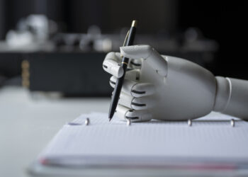 robotic hand holding a pen over a notebook