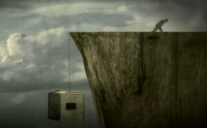 screengrab from Tom Waits video, Tom pulling a house up a cliff using a rope
