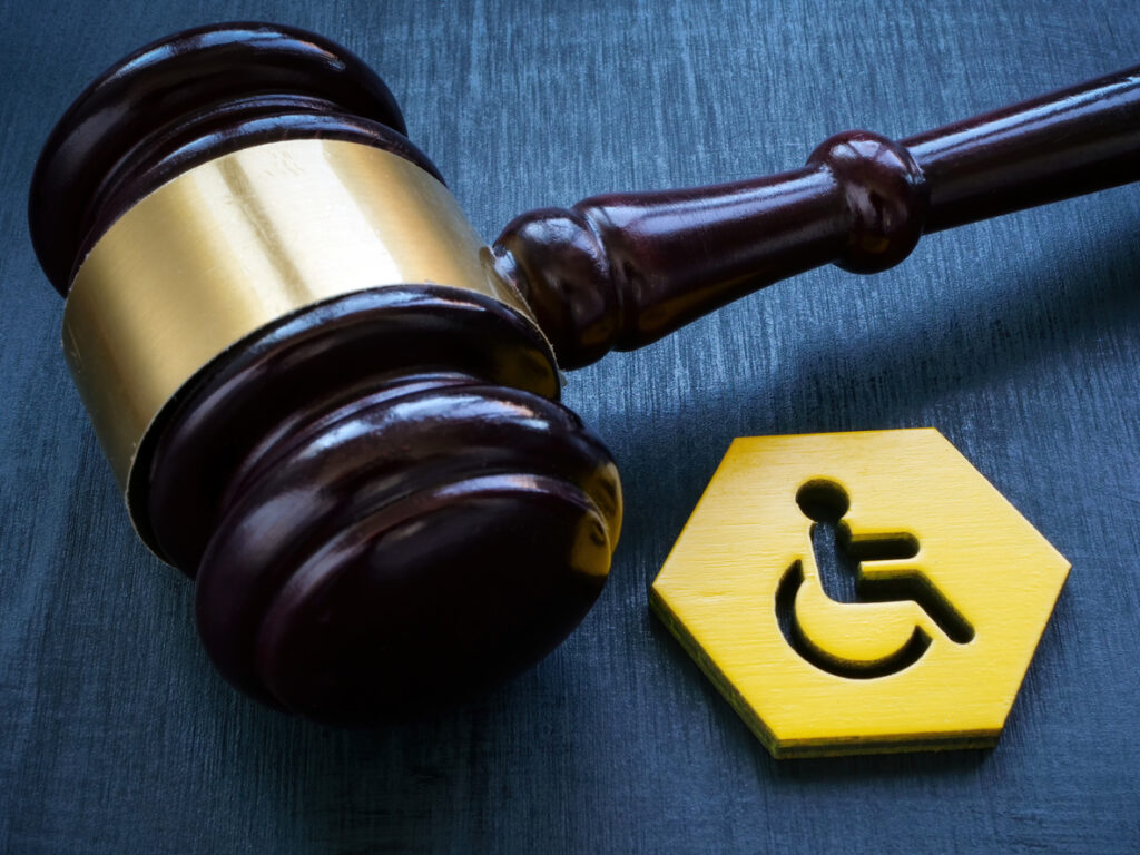 A gavel and a disability person sign