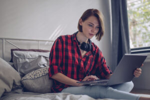 woman sitting in bed using laptop computer