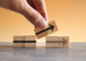 Hand holding wooden cubes with arrow icon, moving one out of position to point to a new direction