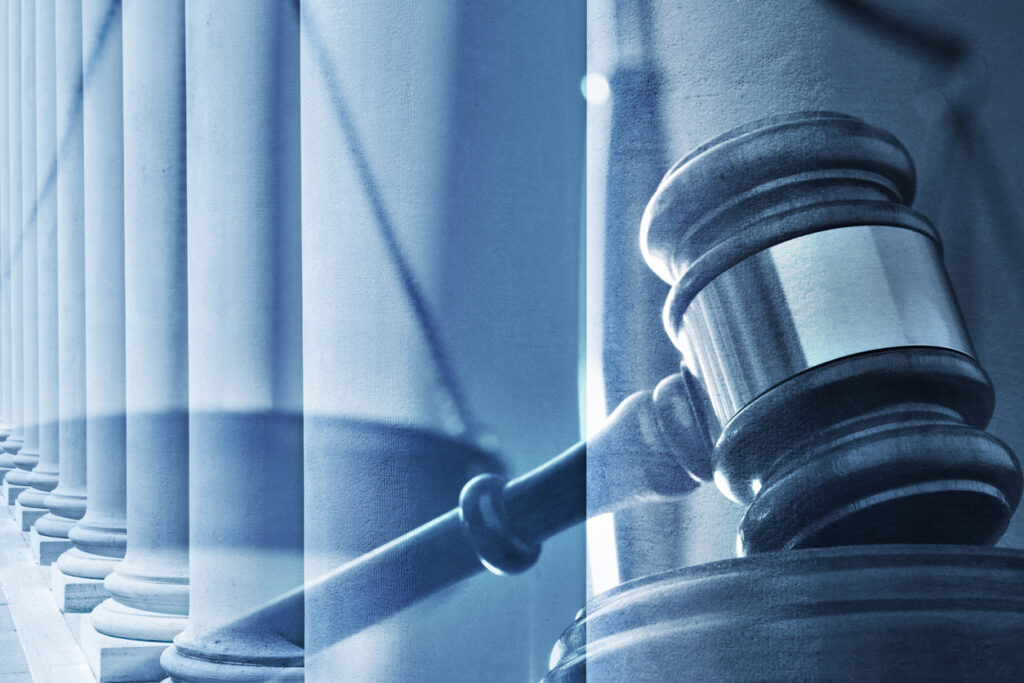 A multiple exposure of a wooden gavel and a long row of Tuscan order columns. A blue color cast dominates the scene.