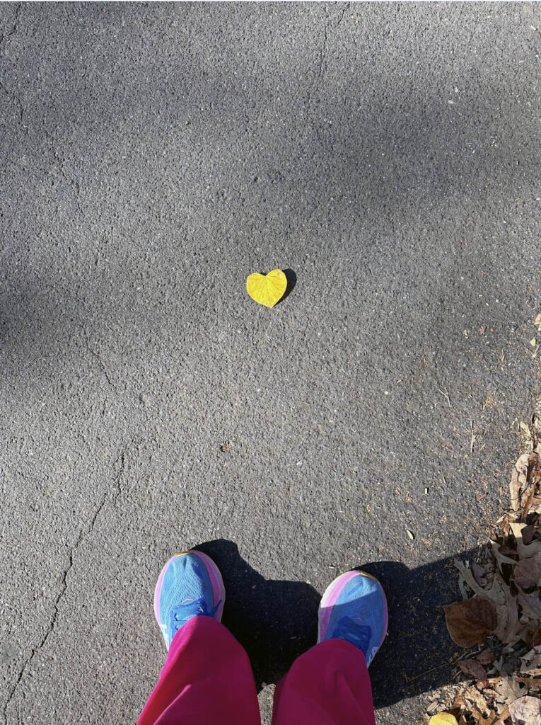 heart shaped leaf on the ground by the feet of an individual, unsurprisingly clad in pink