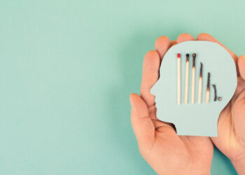 cutout shape of a human head held in a pair of hands. Inside the head are matches at varying levels of burntness