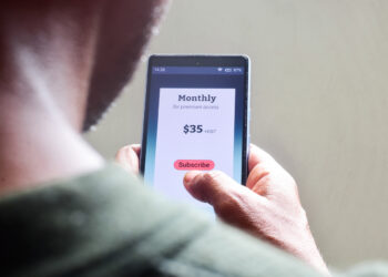 view over the shoulder of a man managing a subscription service payment on a phone