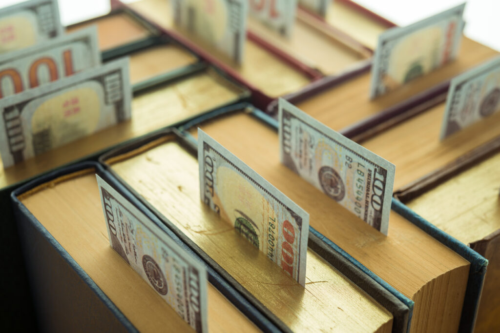 Us currency sticking out of the top of a group of textbooks