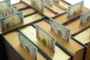 Us currency sticking out of the top of a group of textbooks