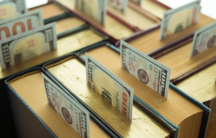 Us currency sticking out of the top of a group of textbooks