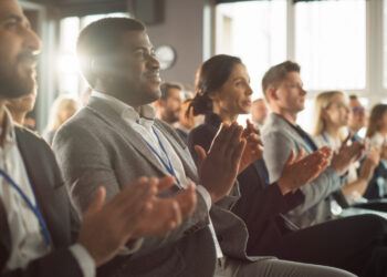 people sitting in the audience at a conference applauding