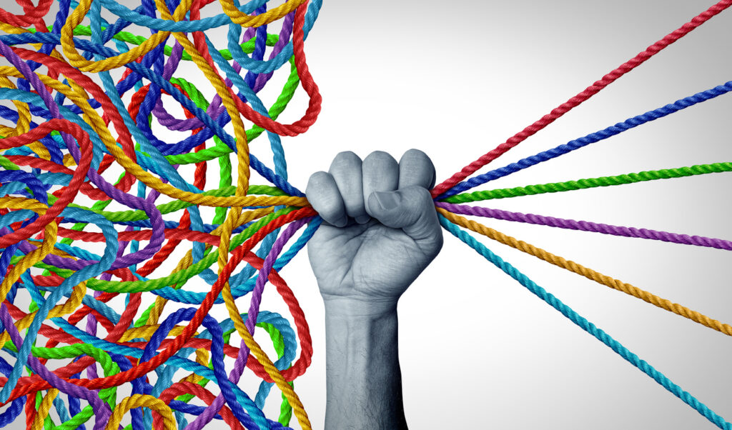 Hand grasping multicolored yarn, where the threads are taught on one side and tangled on the other side of the hand.