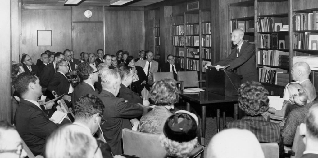 Black and white archival photograph of J. Robert Oppenheimer speaking at the dedication of the Niels Bohr Library in its new reading room at the American Institute of Physics headquarters in New York City, September 26h, 1962.