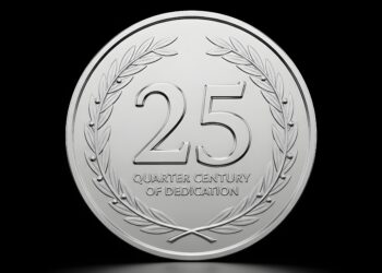 A silver coin on a black background. The coin reads "Celebrating a Quarter Century of Dedication"
