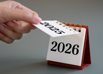 hand flipping calendar page turning from 2025 to 2026,