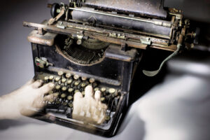 photo of ghostly hands typing on an antique typewriter