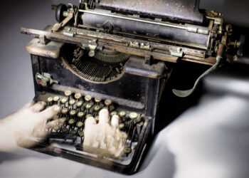 photo of ghostly hands typing on an antique typewriter