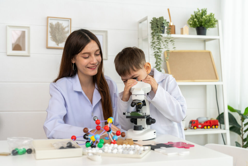 child using microscope being guided by a parent